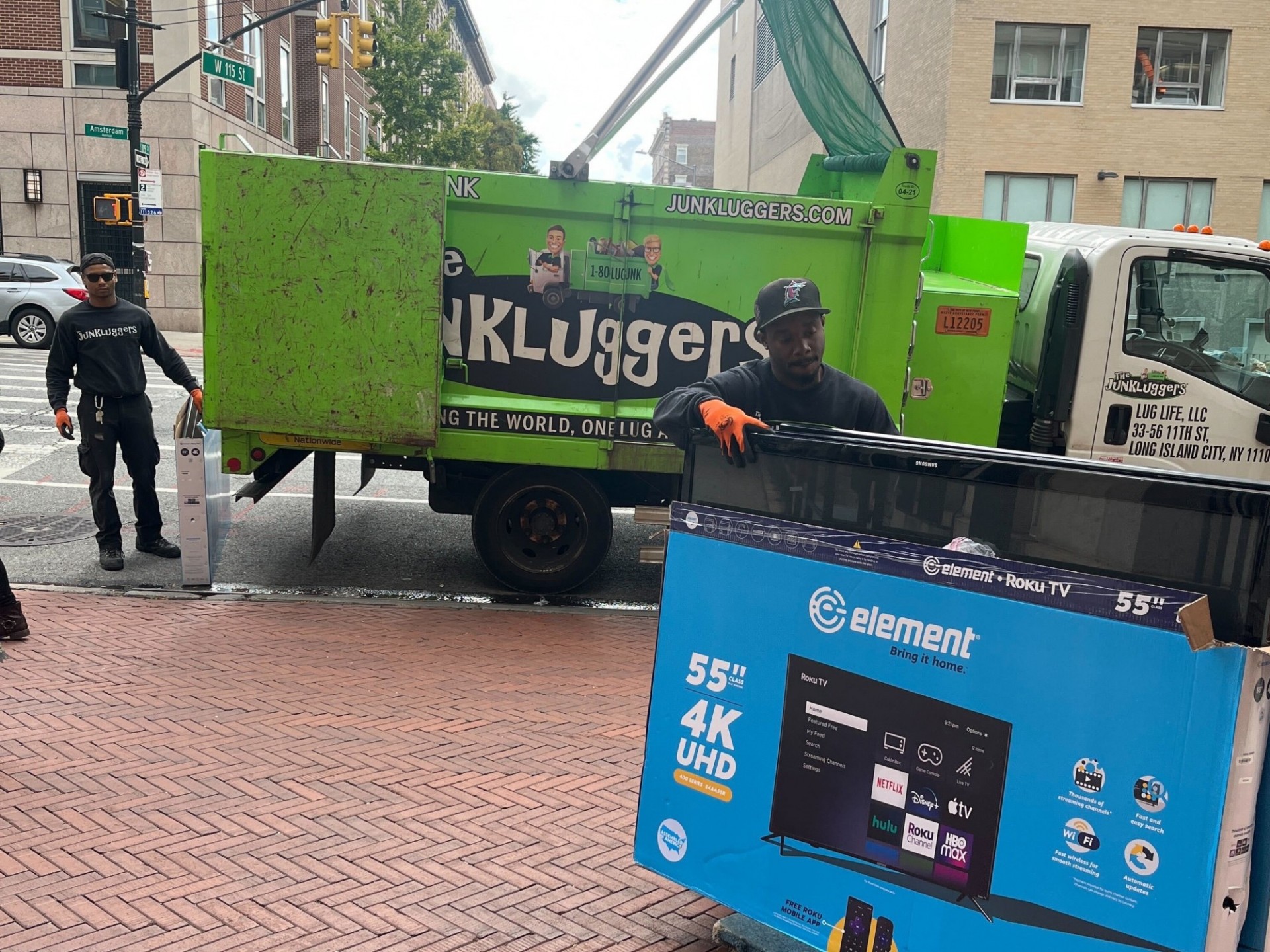 Junkluggers employees loading a gently-used 55 inch TV into a truck.
