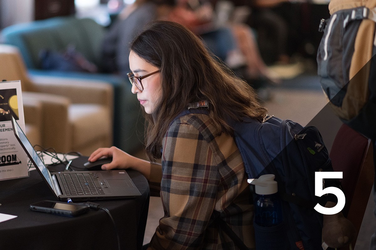 #5: a student sits at a table working on her laptop